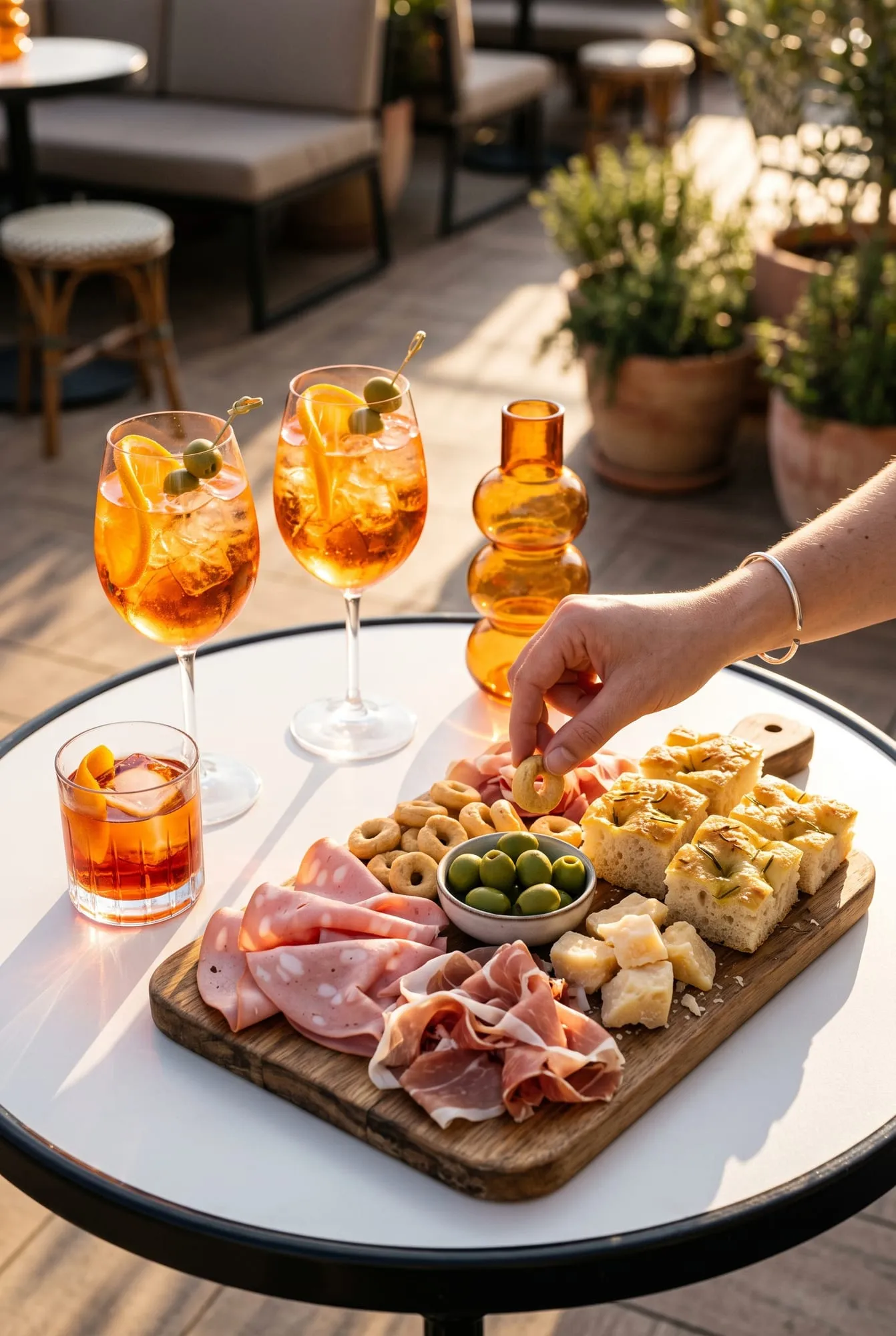 Deux spritz et un negroni en terrasse, au soleil couchant, devant une planche de mortadelle, jambon de Parme, taralli, olives vertes, parmesan et focaccia