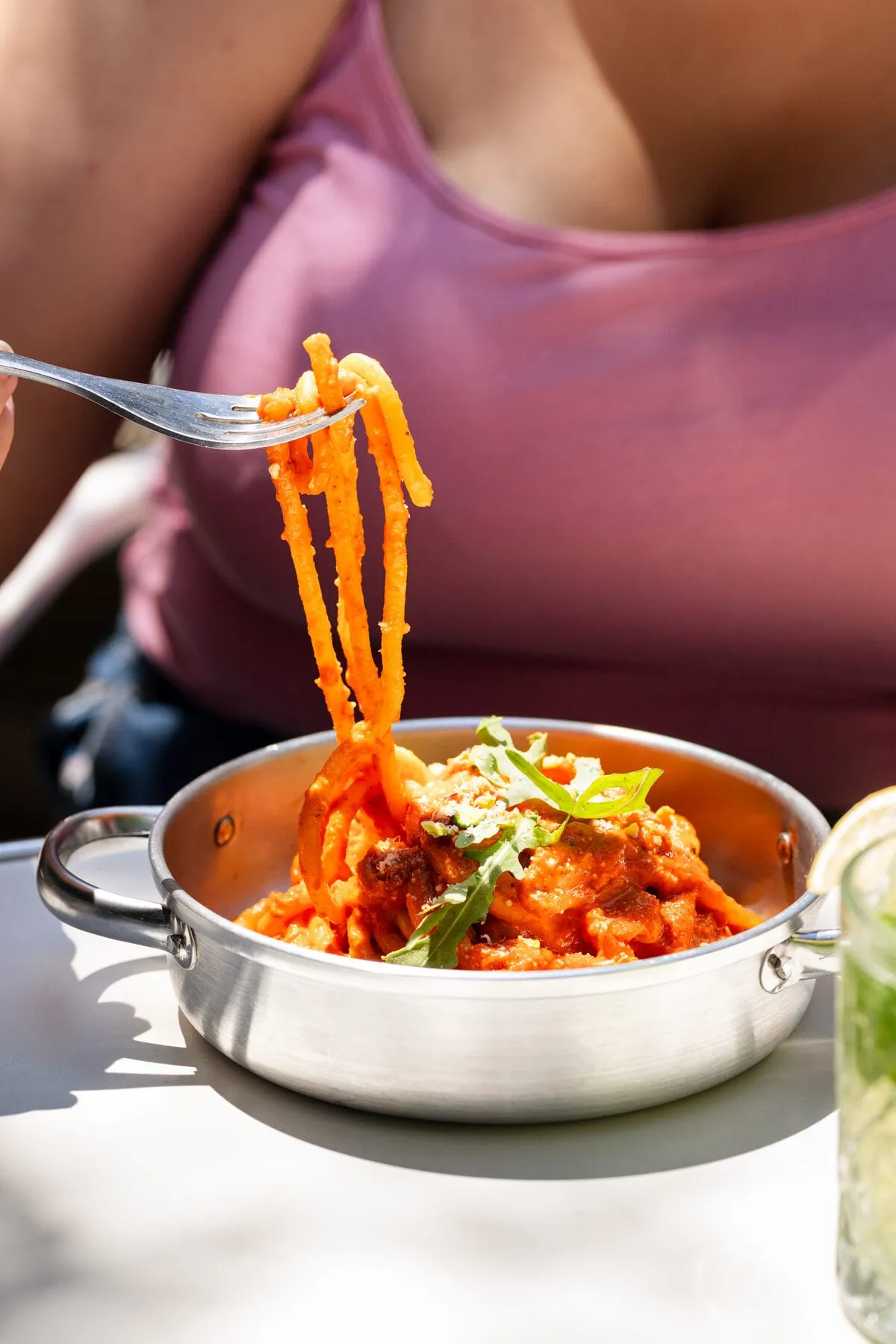 Pâtes à la sauce tomate et roquette tirées à la fourchette d’un plat en inox, en terrasse
