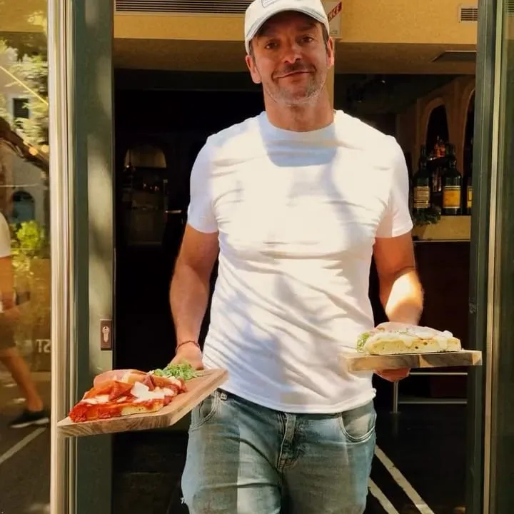 Un membre de l’équipe sort sur le pas de la porte, une planche de foccapizza dans chaque main